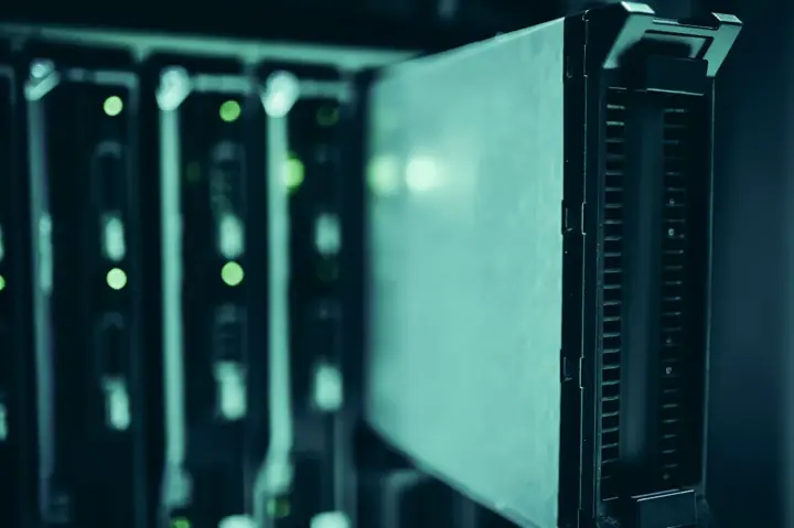 Close-up of a row of rack-mounted servers with green status lights in a dimly lit data centre