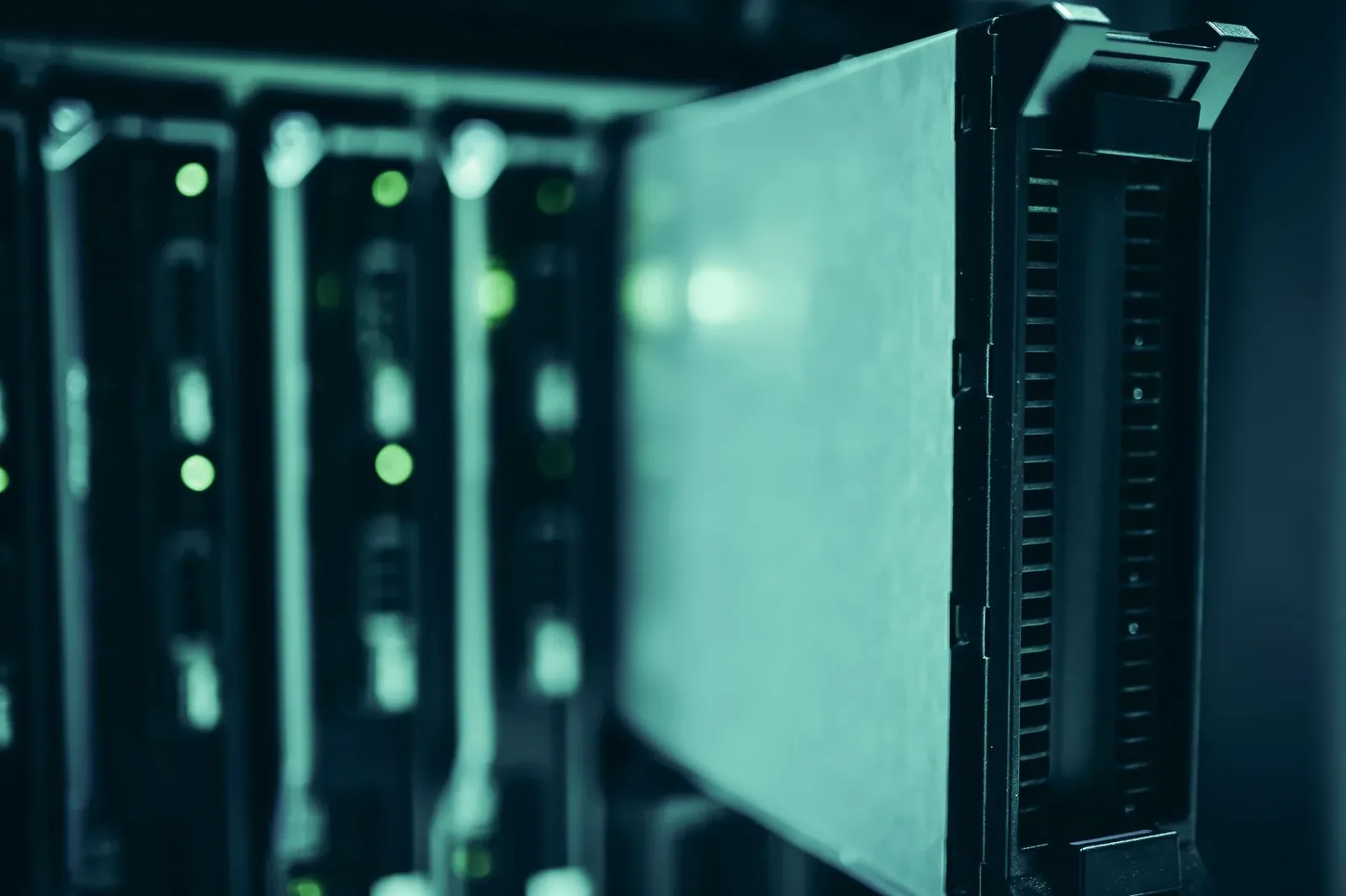 Close-up of a row of rack-mounted servers with green status lights in a dimly lit data centre