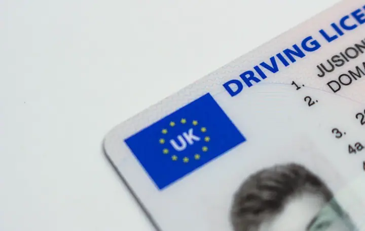 Close-up of the corner of a plastic photocard driving licence with a blue EU-style flag panel marked UK and the words 'Driving Licence'
