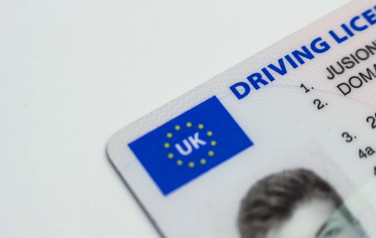 Close-up of the corner of a plastic photocard driving licence with a blue EU-style flag panel marked UK and the words 'Driving Licence'