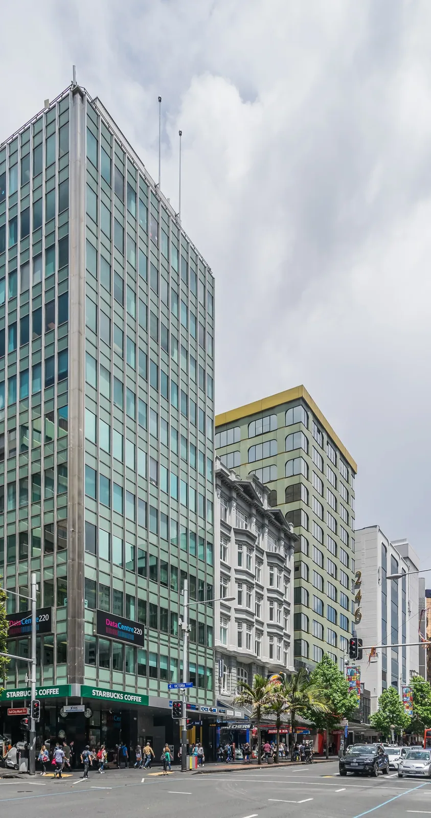 Office buildings along Queen Street in central Auckland, with pedestrians on the footpath and cars on the road