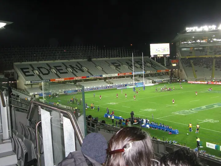 A rugby match under floodlights at Eden Park, seen from high in the stand, with the words EDEN PARK spelled out in the seats of the opposite stand