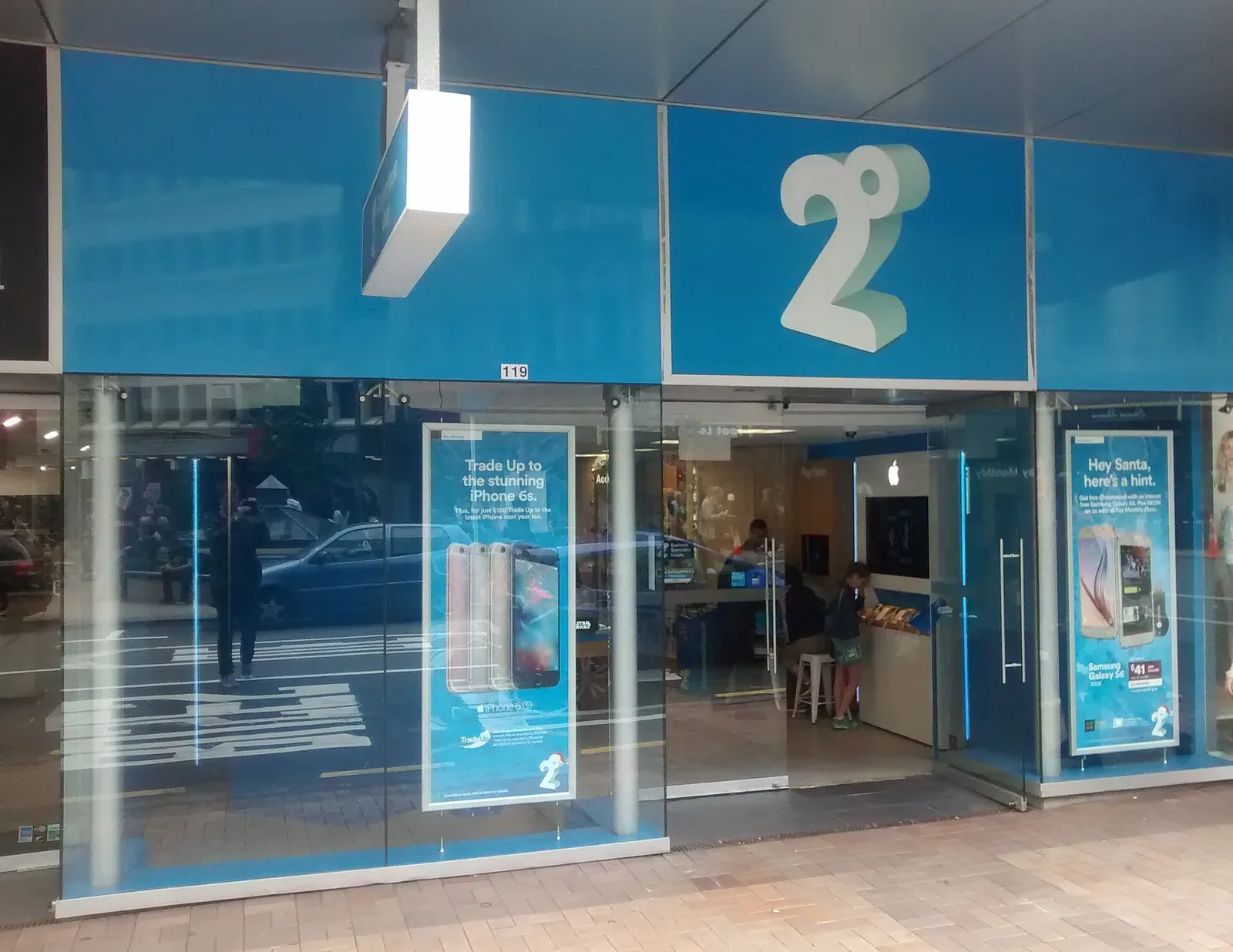 Shopfront of a 2degrees retail store with blue signage and a large white 2degrees logo above glass doors, with phone advertising posters in the windows