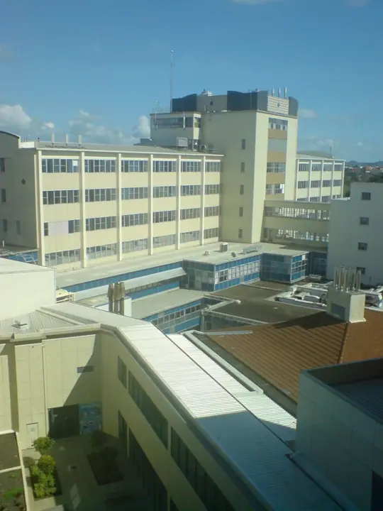 View over the rooftops and multi-storey cream-coloured buildings of a large hospital complex under a blue sky