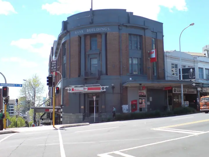 A corner brick building marked 'Bank Buildings' with red Westpac signage at a city street intersection under a blue sky