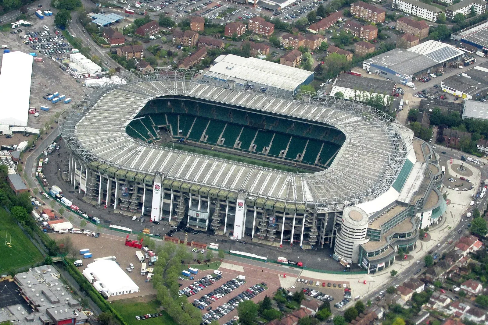 Aerial view of Twickenham Stadium, a large enclosed rugby stadium with a green pitch, surrounded by car parks and houses