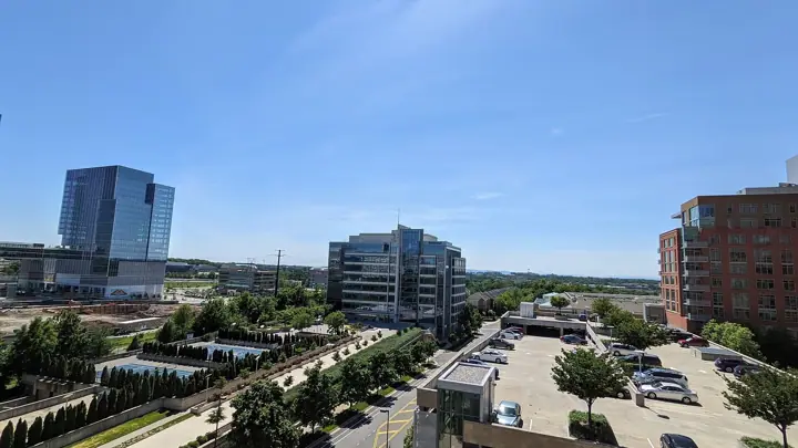 Elevated view over Reston, Virginia, showing glass office buildings, landscaped grounds and a car park under a clear blue sky.