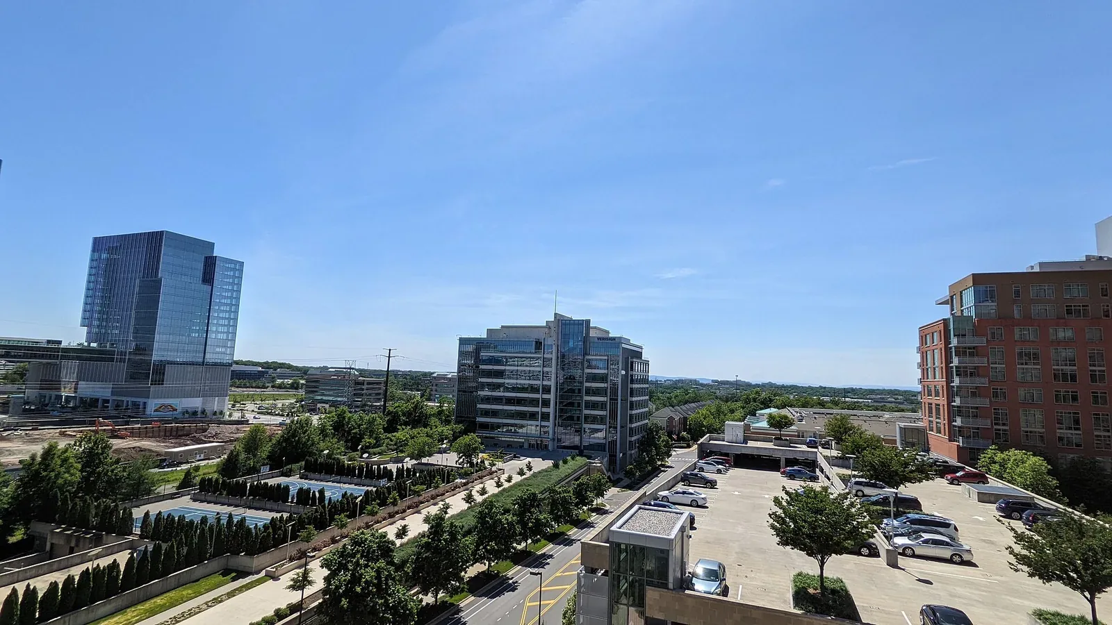 Elevated view over Reston, Virginia, showing glass office buildings, landscaped grounds and a car park under a clear blue sky.